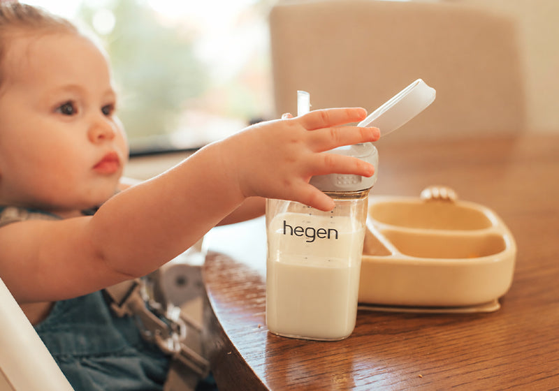 Susu UHT untuk anak 1 tahun diminum dari straw cup di kursi makan